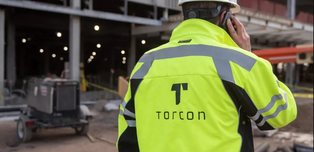 construction worker talking on the phone wearing a yellow torcon jacket